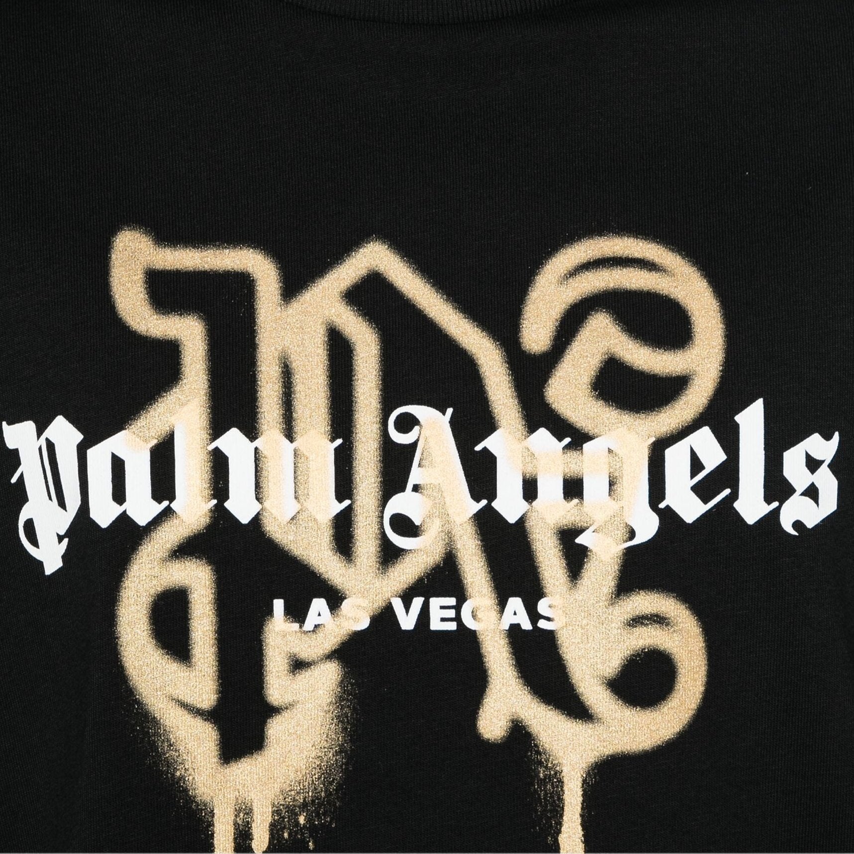 The Palm Angels Las Vegas Monogram Sprayed Logo T-Shirt showcases a black background adorned with the iconic Palm Angels logo in white ornate Gothic font. Below the logo, "Las Vegas" is displayed in smaller white block letters, complemented by gold stylized lettering elements that create a luxurious Las Vegas Monogram effect against the dark backdrop.