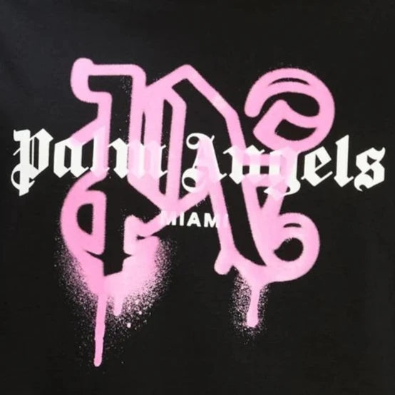 The Palm Angels Miami Monogram Sprayed Logo T-Shirt, featuring the "Palm Angels" logo in white gothic font against a black background, subtly displays "Miami Monogram" beneath. A striking pink graffiti-style "N" behind the text adds an edgy flair.