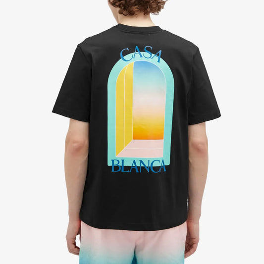 The person sports a Casablanca L'Arc Colore T-Shirt Black made from organic cotton, featuring the signature arch logo in pastel and "CASA BLANCA" on the back, complemented by blue and pink gradient shorts.