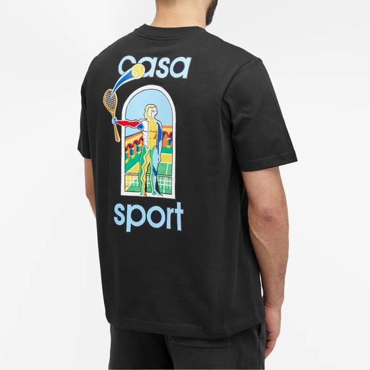 A person wearing the Casablanca Le Jeu Colore T-Shirt Black, featuring "casa sport" on the back, an illustration of a tennis player swinging a racket inside an arched frame, and colorful abstract elements. This embodies Casablanca's sport-inspired leisurewear in organic cotton.