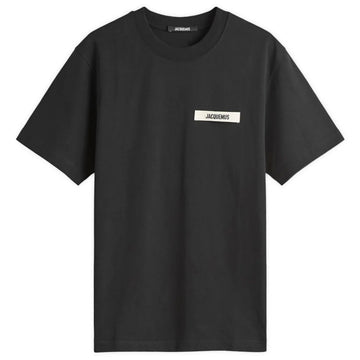 The Jacquemus Gros Grain Logo T-Shirt in black is made from organic cotton fleece, featuring a classic crew neckline, short sleeves, and a chest label with an embroidered grosgrain "JACQUEMUS" logo in bold white letters.