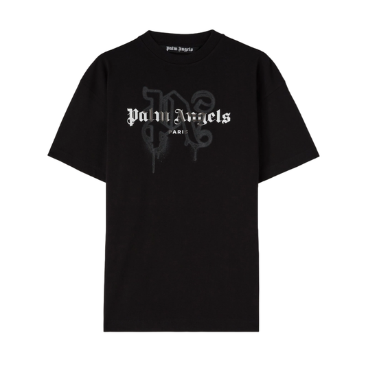 The Palm Angels Paris Monogram Sprayed Logo T-Shirt is a black cotton jersey featuring "Palm Angels" in white Gothic-style letters on the chest with "Paris" written underneath. A subtle, faint overlapping letter "P" in the background completes this striking Monogram Logo Tee.