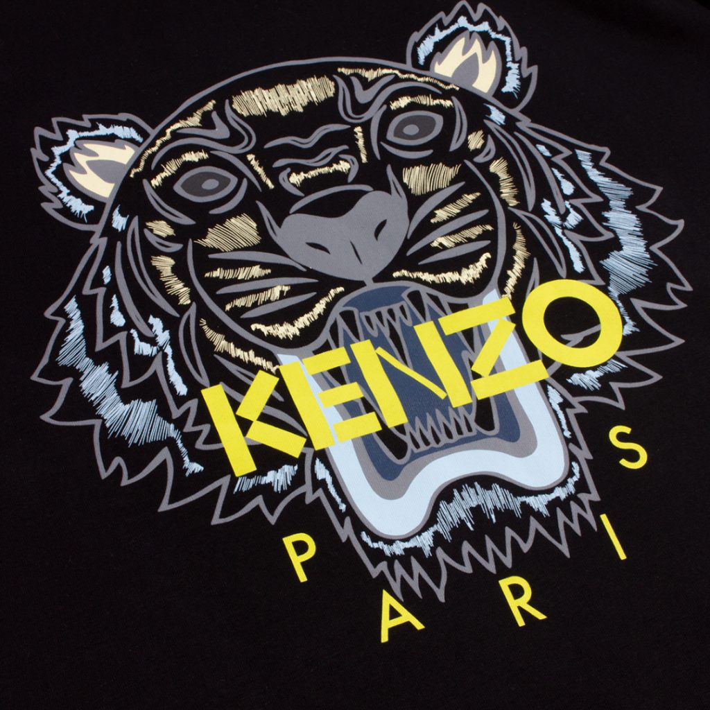 Experience the vibrant design of the Kenzo Classic Tiger T-Shirt, featuring a stylized, colorful illustration of a tiger's face on a black background. The bold yellow "KENZO" lettering is prominently displayed with "PARIS" beneath it. Made from premium cotton, it ensures ultimate comfort.