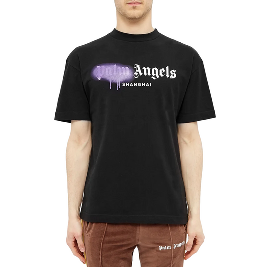 Someone is nailing the streetwear style with a Palm Angels Shanghai Sprayed Logo T-Shirt, which showcases "Shanghai" in white lettering beneath a purple spray-paint design. They're effortlessly teaming it up with brown Palm Angels pants for a complete and stylish ensemble.