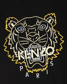 The Kenzo Embroidered Tiger T-Shirt features premium black cotton fabric adorned with a detailed embroidered tiger head in blue and yellow. "Kenzo" is prominently displayed across the tiger's face, with "Paris" elegantly positioned underneath, making this Kenzo piece a standout addition to any wardrobe.