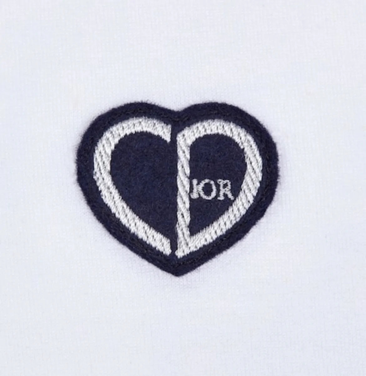 Introducing the Dior "CD" Heart Patch T-Shirt, this remarkable piece features a heart-shaped logo with a striking black and white split design. The letters "C" grace the left side, while "D" adorns the right, inspired by Dior's iconic heart patch for an elegant touch to any cotton jersey ensemble.